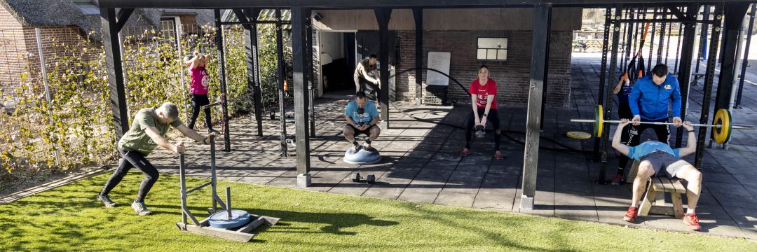 Mensen trainen onder het krachttrainingsrek van Reestdal Outdoor